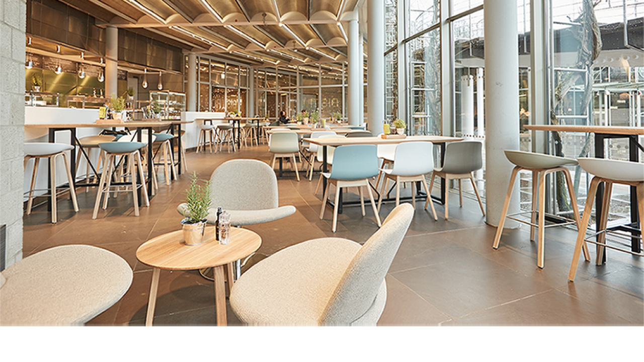 Modern café interior with wooden tables and chairs, large windows, and pendant lighting.